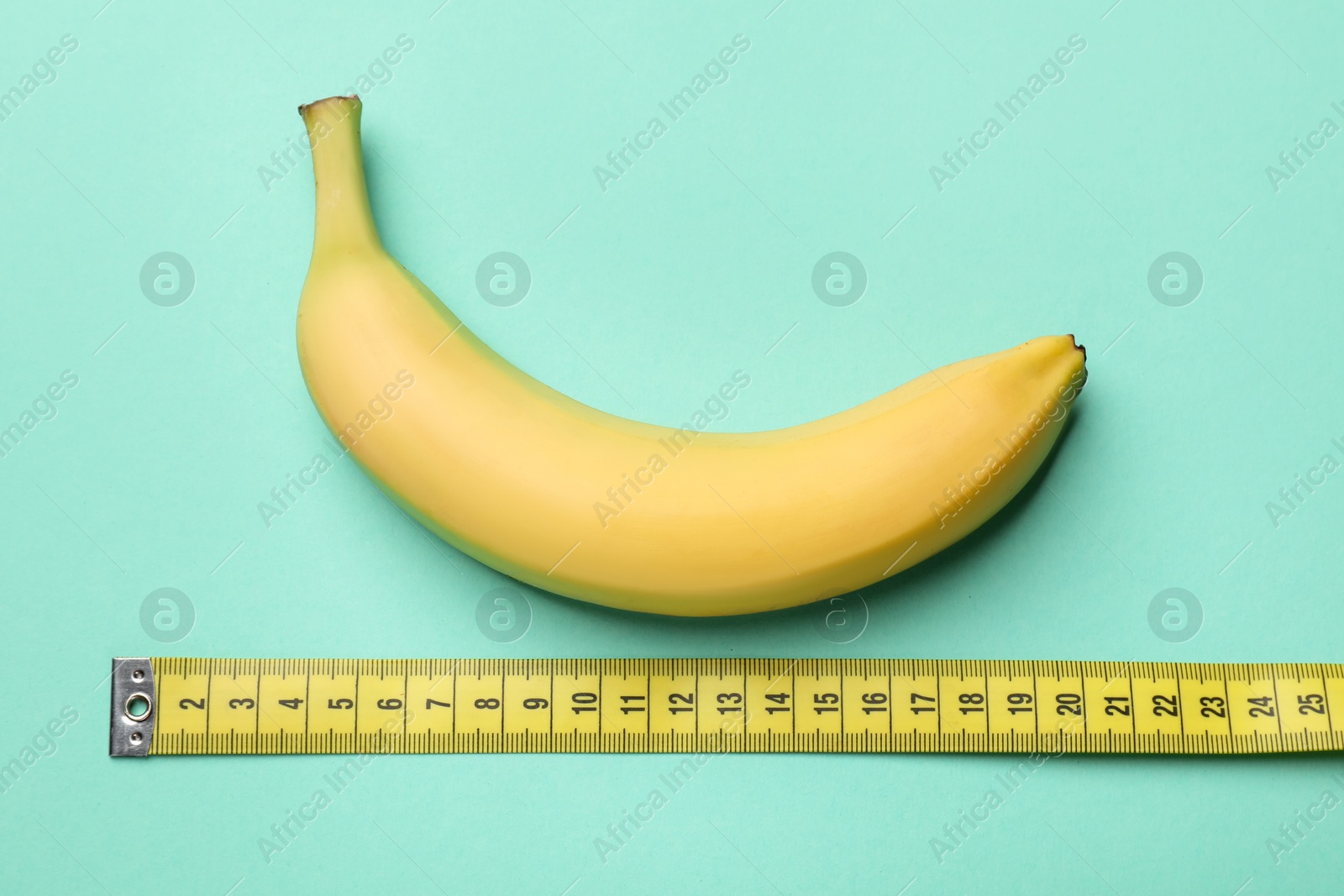 Sex education. Banana with measuring tape on turquoise background, flat lay Photo of Sex education. Banana with measuring tape on turquoise background, flat lay
