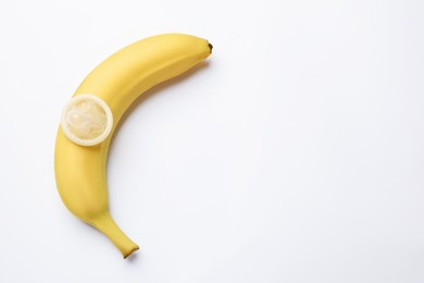Photo of Sex education. Banana with condom on white background, top view. Space for text