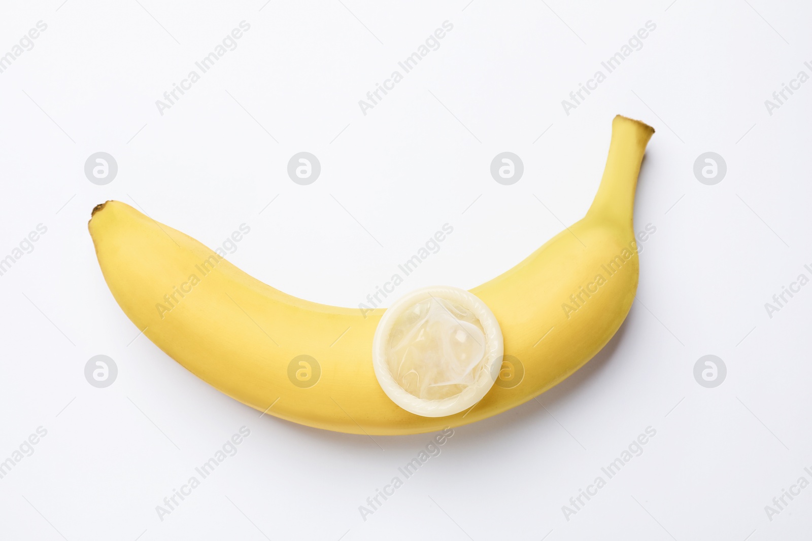 Sex education. Banana with condom on white background, top view Photo of Sex education. Banana with condom on white background, top view
