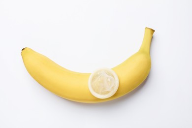 Photo of Sex education. Banana with condom on white background, top view