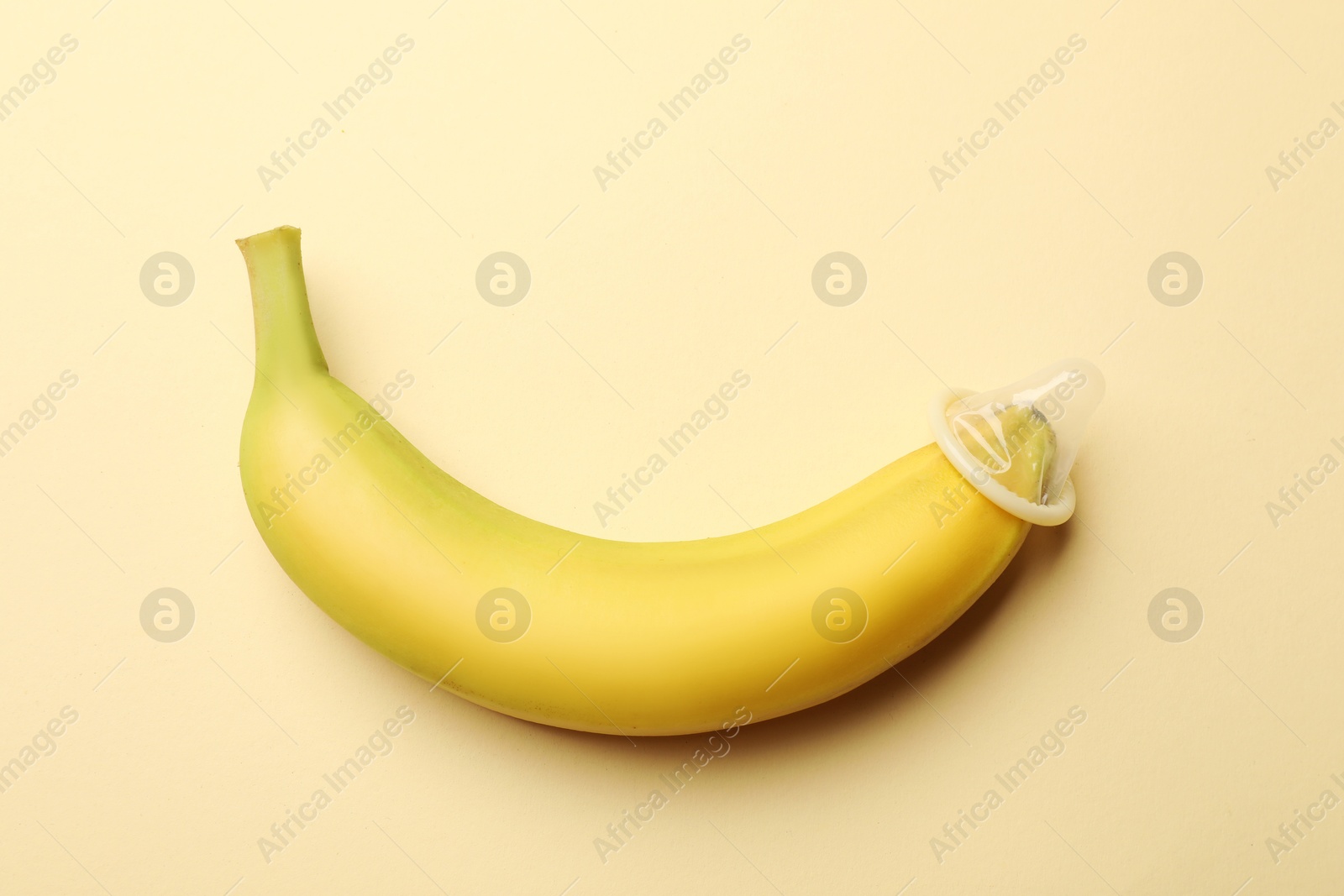 Sex education. Banana with condom on beige background, top view Photo of Sex education. Banana with condom on beige background, top view