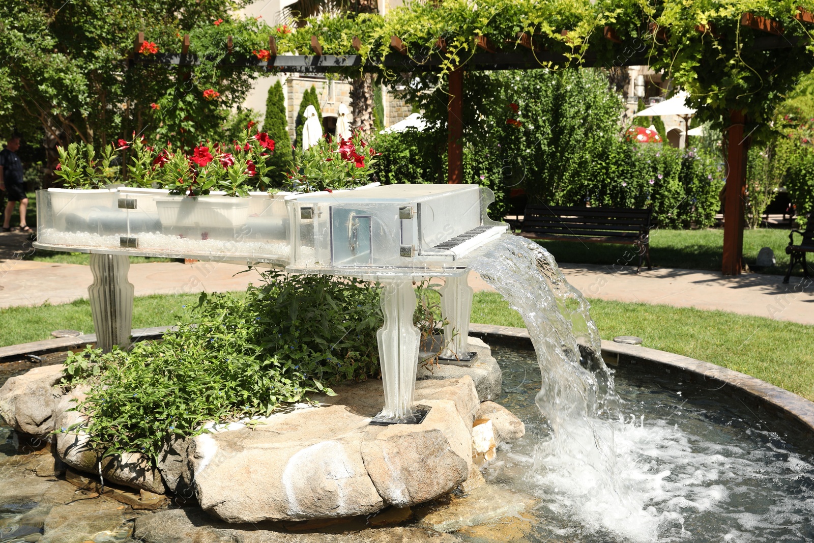Piano shaped fountain decorated with flowers in park Photo of Piano shaped fountain decorated with flowers in park