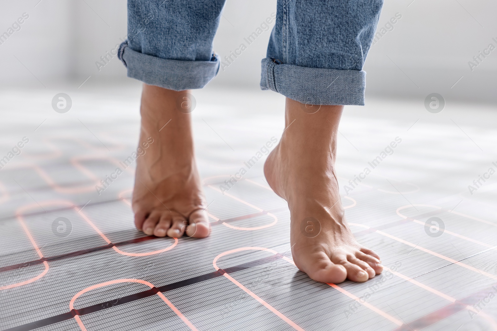 Woman walking barefoot on warm floor at home, closeup. Underfloor heating system seen through laminate Image of Woman walking barefoot on warm floor at home, closeup. Underfloor heating system seen through laminate
