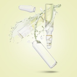 Image of Ampoules and splash of medical or cosmetic liquid in air against beige background