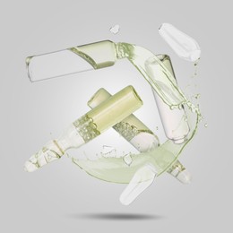 Image of Ampoules and splash of medical or cosmetic liquid in air against grey background