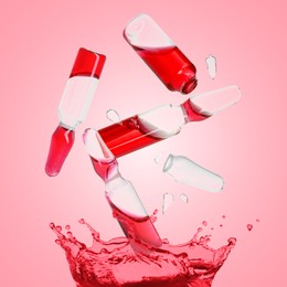 Image of Ampoules and splash of medical or cosmetic liquid in air against pink background