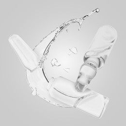 Image of Ampoules and splash of medical or cosmetic liquid in air against grey background
