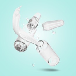 Image of Ampoules and splash of medical or cosmetic liquid in air against turquoise background
