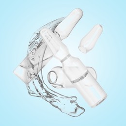 Image of Ampoules and splash of medical or cosmetic liquid in air against light blue background