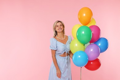 Photo of Smiling woman with bunch of colorful balloons on pink background. Space for text