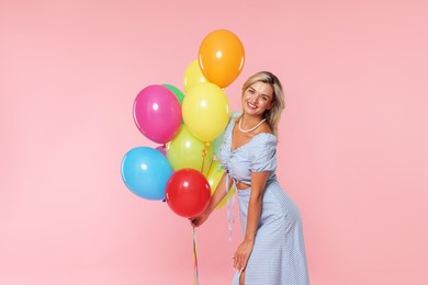 Photo of Smiling woman with bunch of colorful balloons on pink background