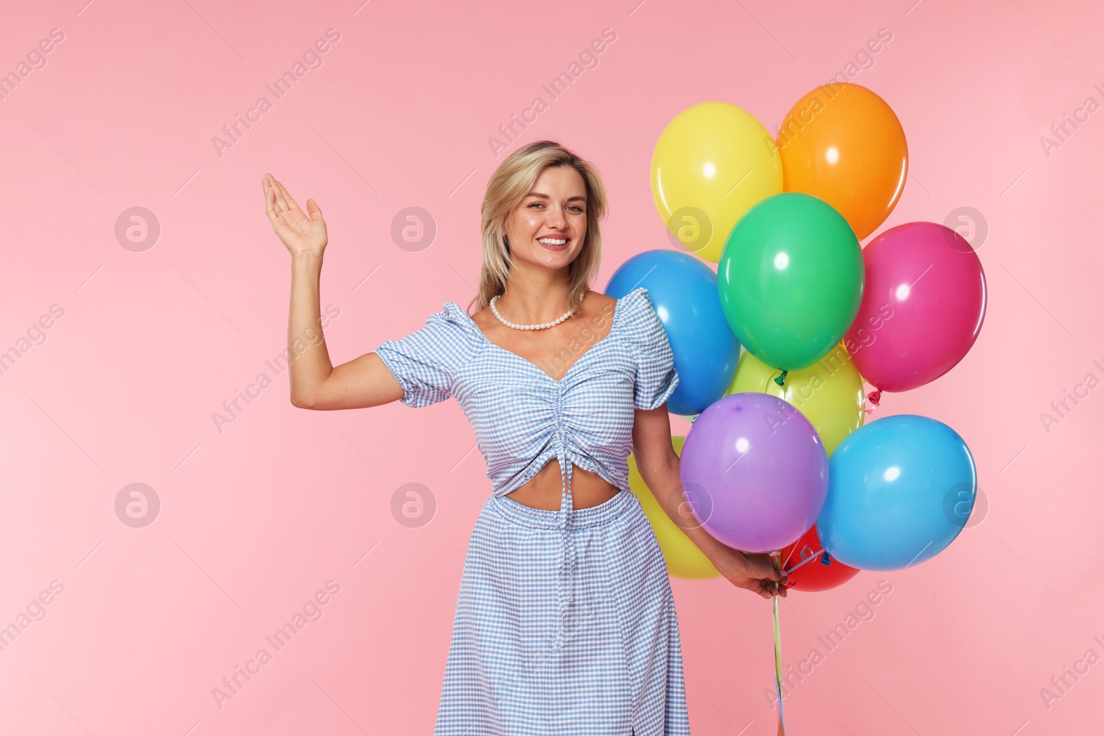 Photo of Smiling woman with bunch of colorful balloons on pink background
