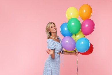 Photo of Smiling woman with bunch of colorful balloons on pink background