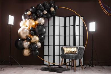 Photo of Stylish photo zone with balloons, armchair and decor in studio