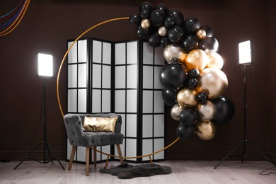 Photo of Stylish photo zone with balloons, armchair and decor in studio