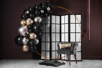Photo of Stylish photo zone with balloons, armchair and decor in studio