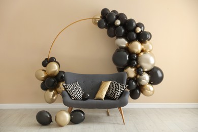 Photo of Stylish photo zone with balloons and sofa near beige wall