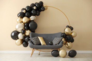 Photo of Stylish photo zone with balloons and sofa near beige wall