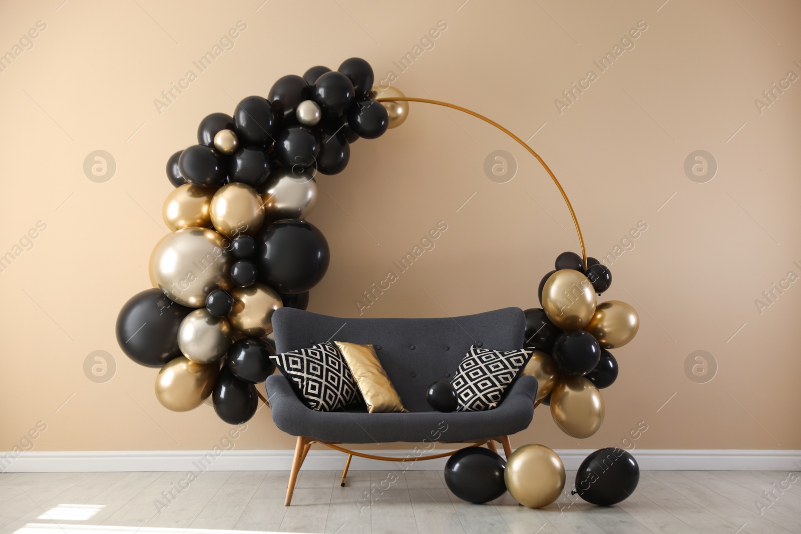Photo of Stylish photo zone with balloons and sofa near beige wall