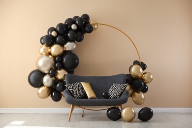 Photo of Stylish photo zone with balloons and sofa near beige wall