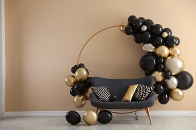 Photo of Stylish photo zone with balloons and sofa near beige wall. Space for text