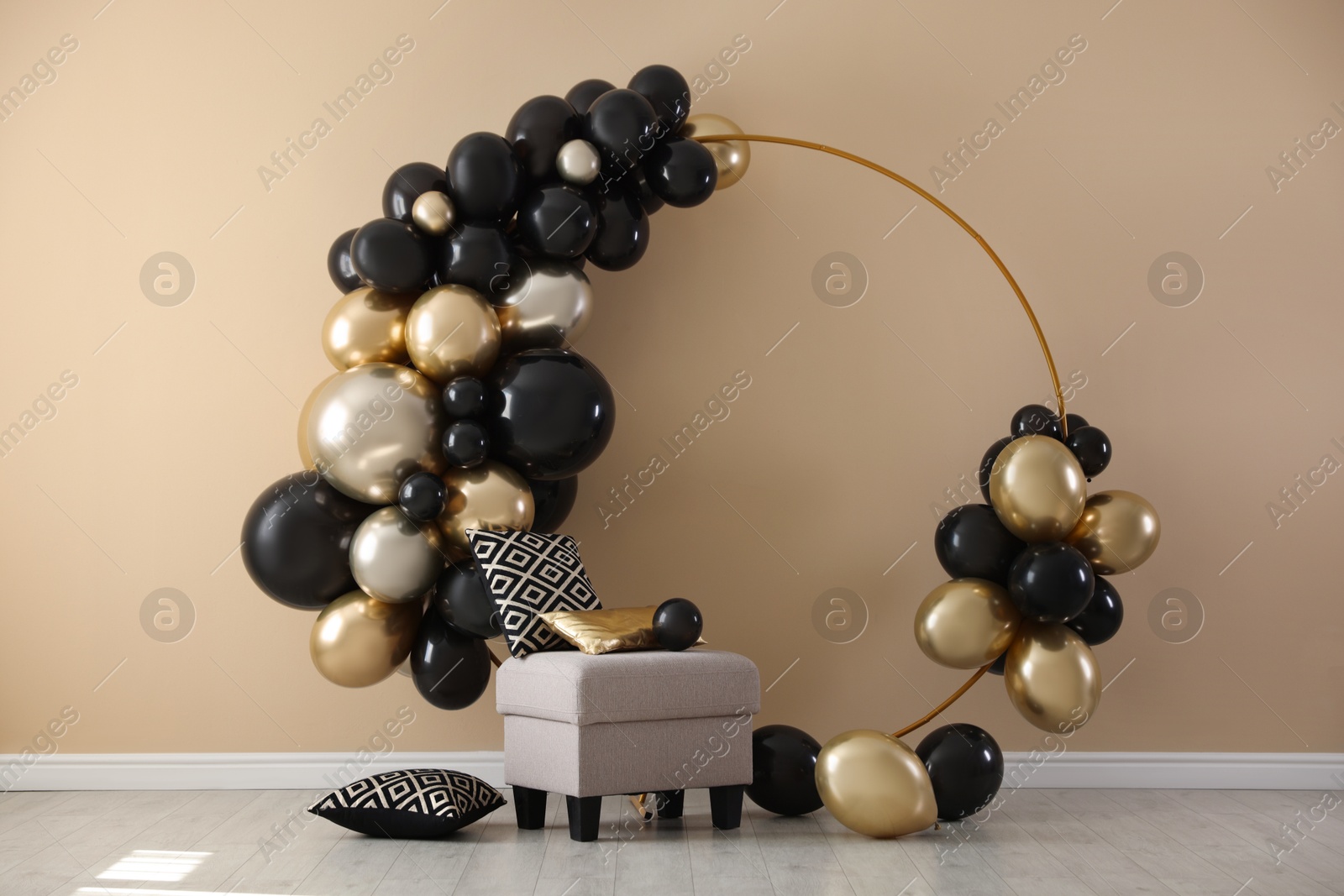 Photo of Stylish photo zone with balloons and pouf near beige wall