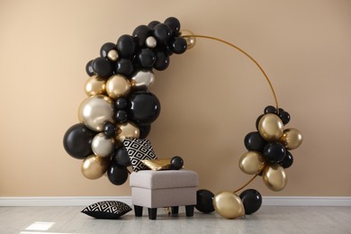 Photo of Stylish photo zone with balloons and pouf near beige wall