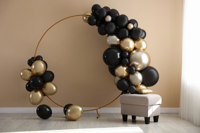 Photo of Stylish photo zone with balloons and pouf near beige wall
