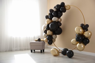 Photo of Stylish photo zone with balloons and pouf near beige wall