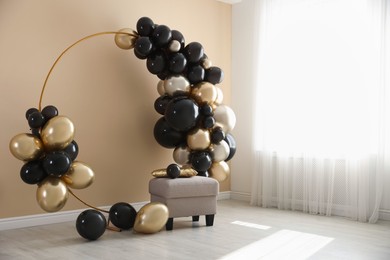 Photo of Stylish photo zone with balloons and pouf near beige wall