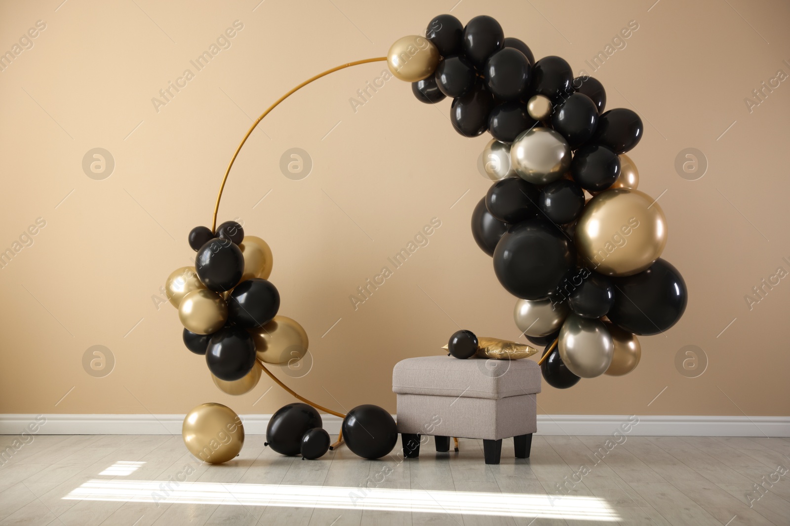 Photo of Stylish photo zone with balloons and pouf near beige wall