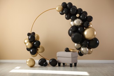 Photo of Stylish photo zone with balloons and pouf near beige wall