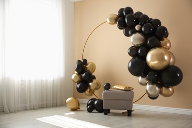Photo of Stylish photo zone with balloons and pouf near beige wall