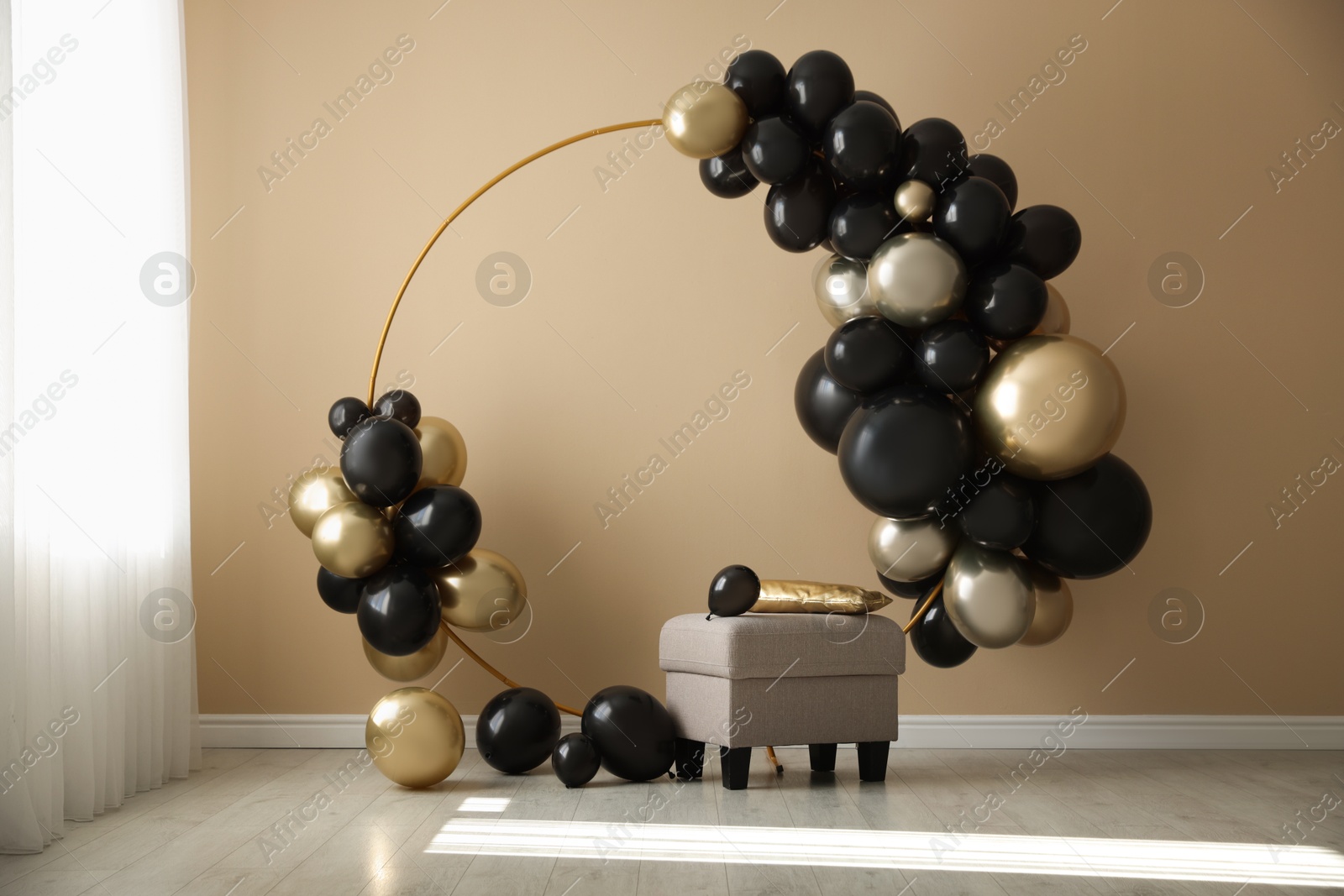 Photo of Stylish photo zone with balloons and pouf near beige wall