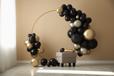 Photo of Stylish photo zone with balloons and pouf near beige wall