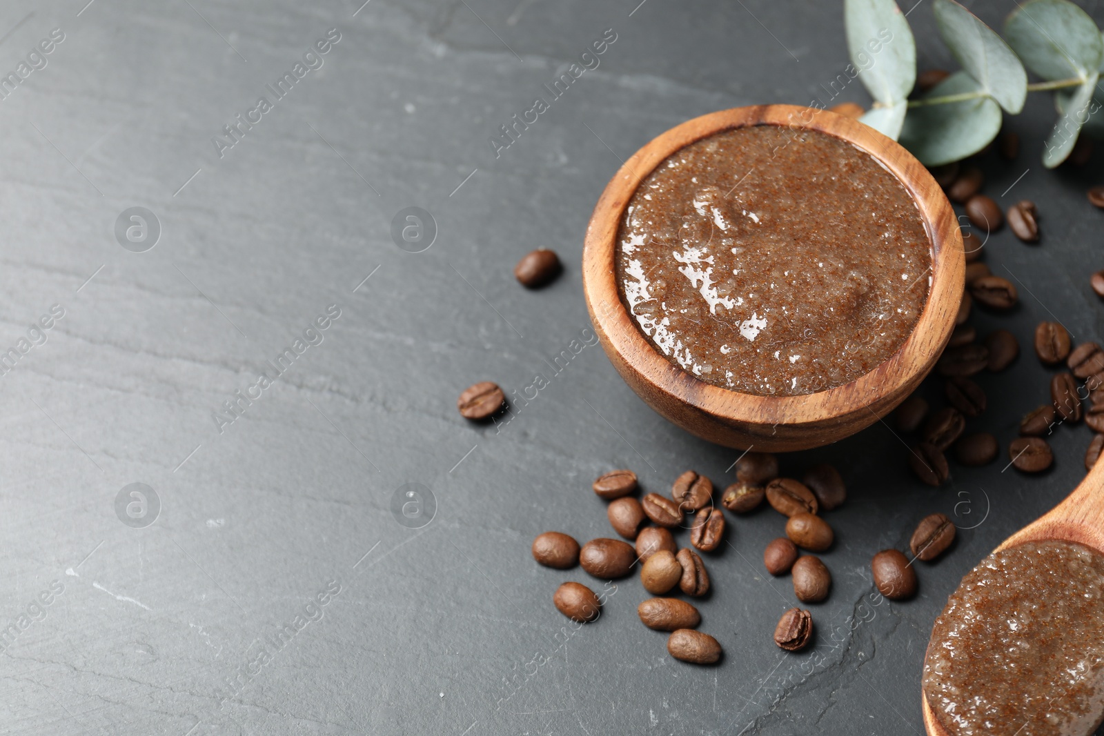 Natural body scrub, coffee beans and eucalyptus leaves on black table, above view. Space for text Photo of Natural body scrub, coffee beans and eucalyptus leaves on black table, above view. Space for text
