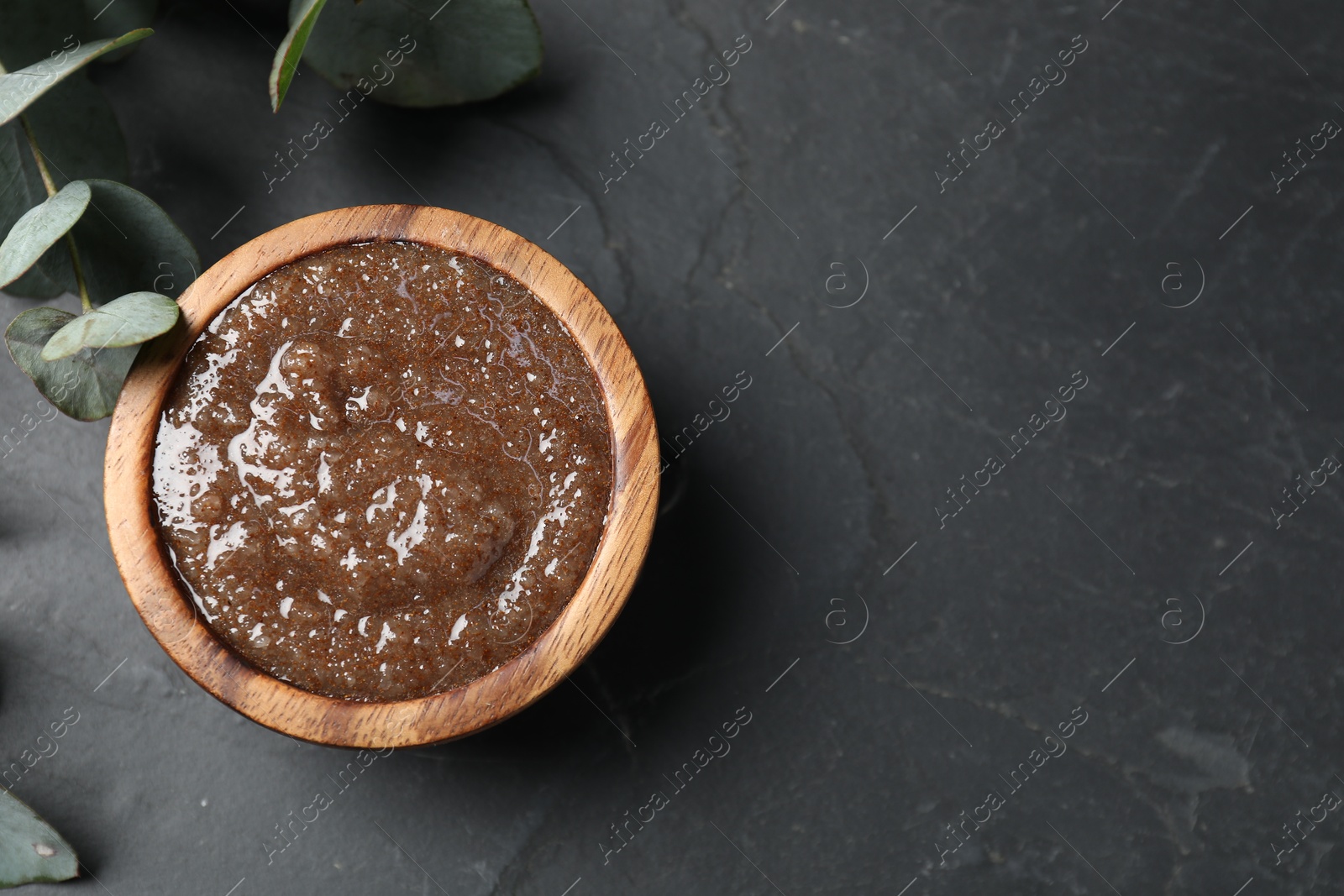 Natural body scrub and eucalyptus leaves on black table, flat lay. Space for text Photo of Natural body scrub and eucalyptus leaves on black table, flat lay. Space for text