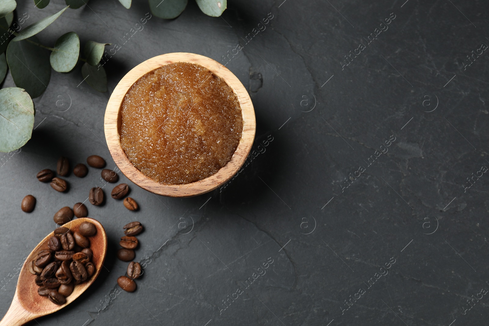 Natural body scrub, coffee beans and eucalyptus leaves on black table, flat lay. Space for text Photo of Natural body scrub, coffee beans and eucalyptus leaves on black table, flat lay. Space for text