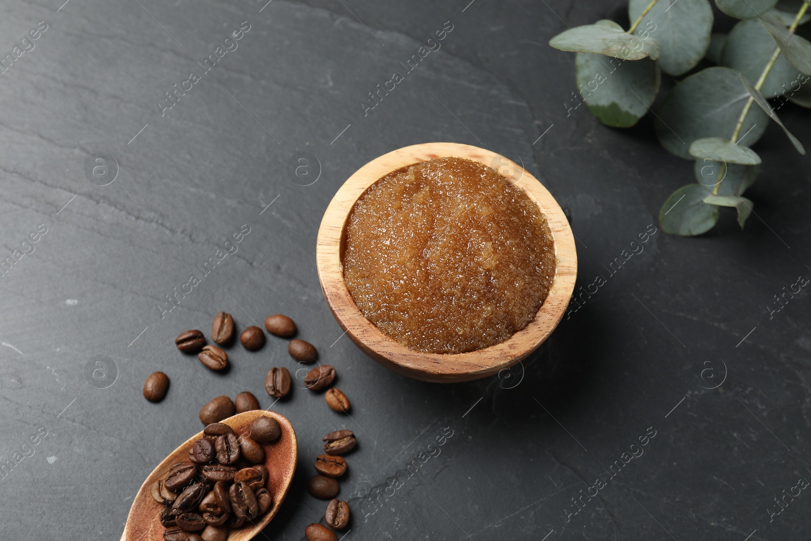 Photo of Natural body scrub, coffee beans and eucalyptus leaves on black table, above view