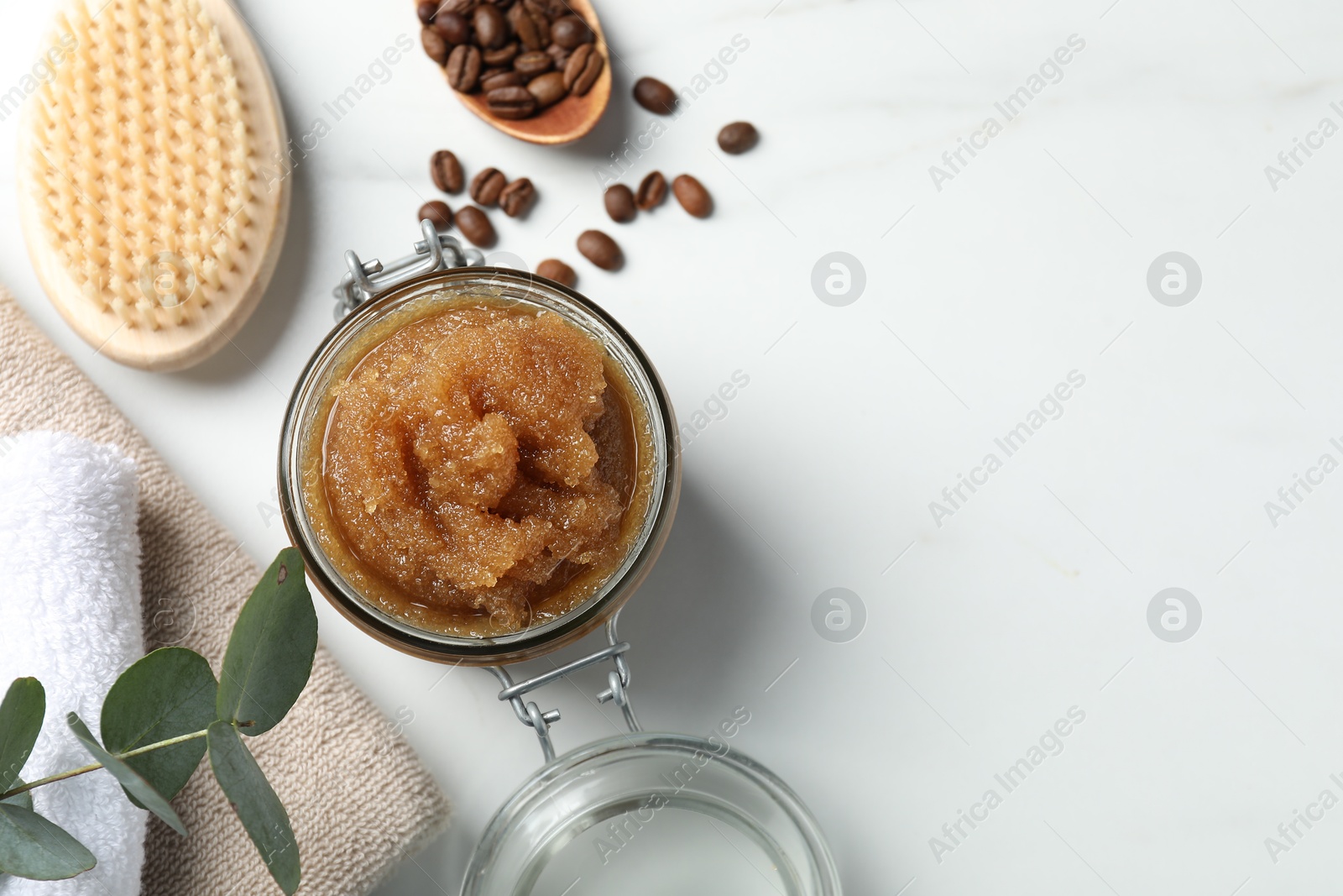 Photo of Natural body scrub, coffee beans and eucalyptus leaves on white table, flat lay. Space for text