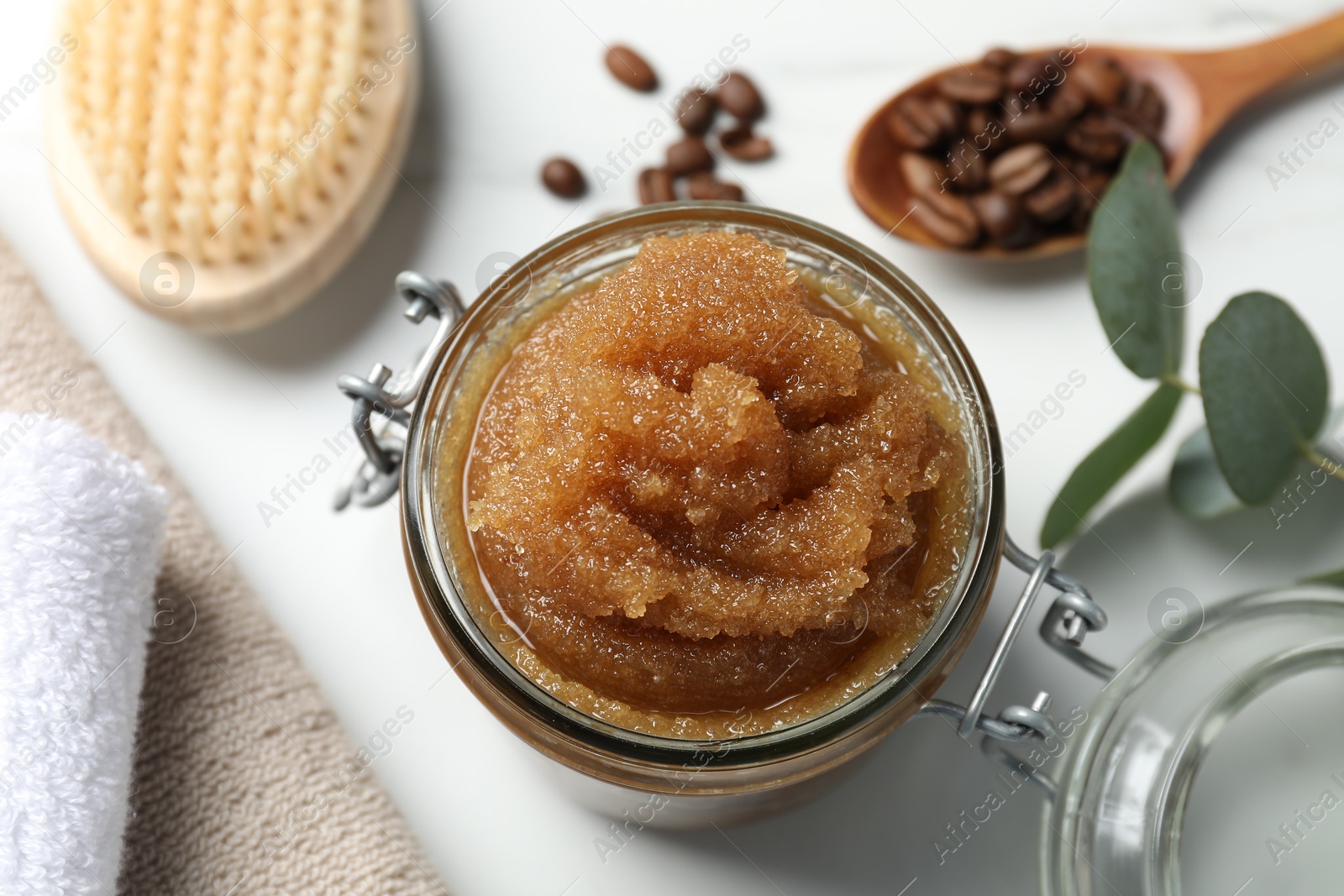 Natural body scrub, coffee beans and eucalyptus leaves on white table, above view Photo of Natural body scrub, coffee beans and eucalyptus leaves on white table, above view