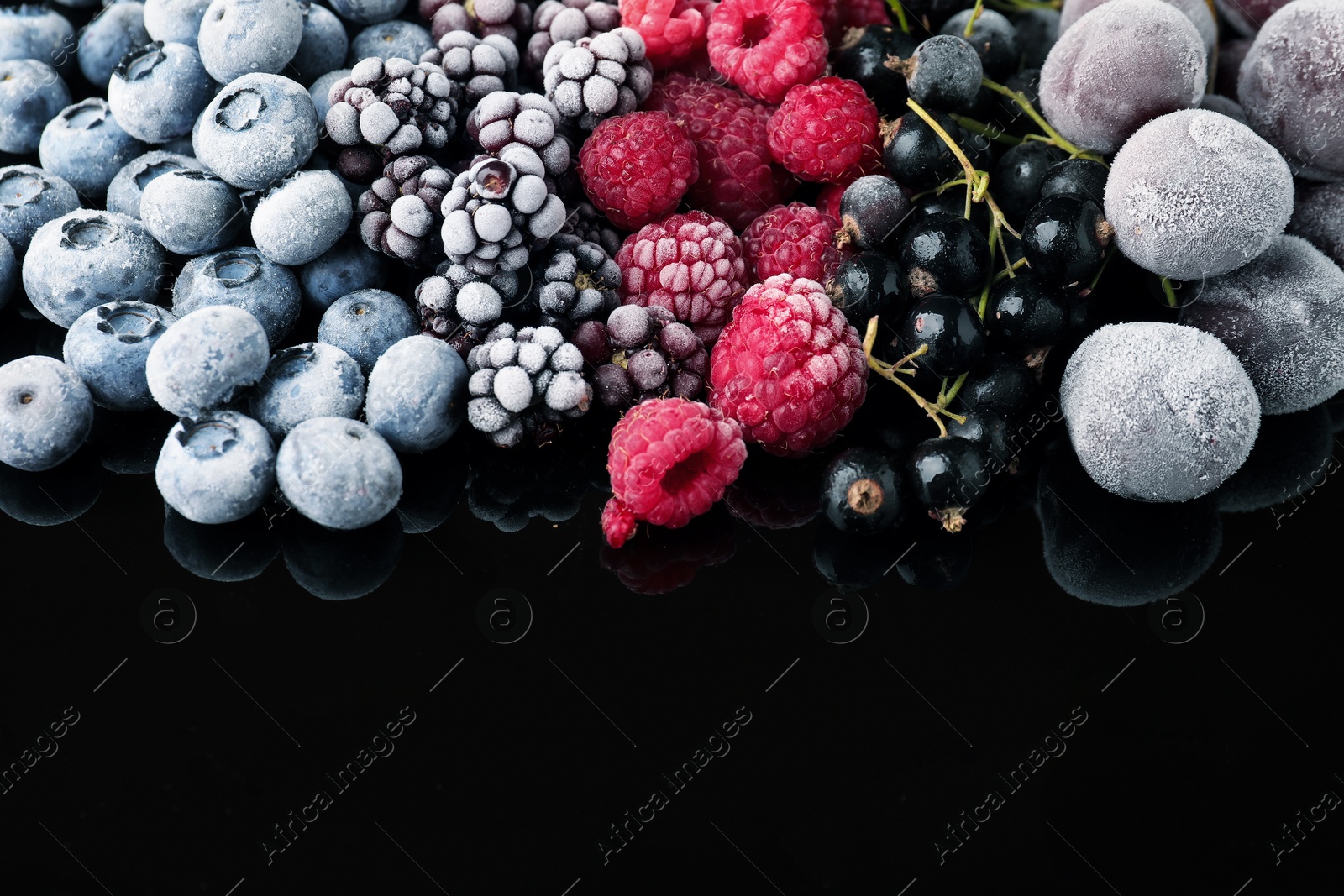 Photo of Many different frozen berries on black table, closeup. Space for text