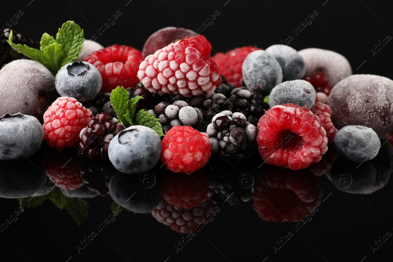Photo of Many different frozen berries and mint on black table, closeup