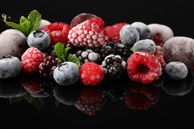 Photo of Many different frozen berries and mint on black table, closeup