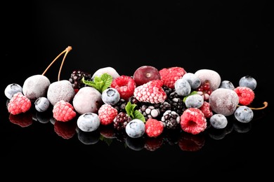 Photo of Many different frozen berries and mint on black table