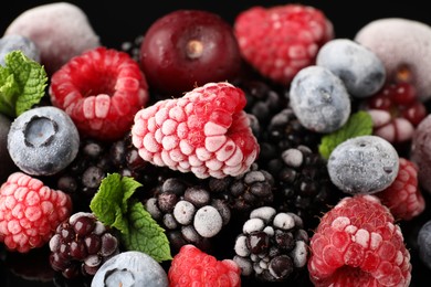 Photo of Many different frozen berries and mint on table, closeup