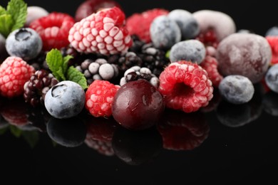 Photo of Many different frozen berries and mint on black table, closeup