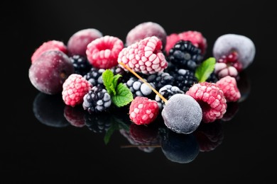 Photo of Many different frozen berries and mint on black table, closeup