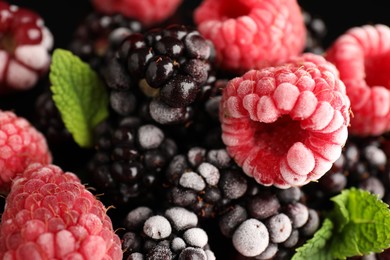 Photo of Many different frozen berries and mint on black background, top view