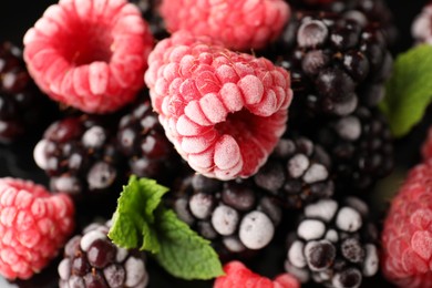 Photo of Many different frozen berries and mint on black background, top view